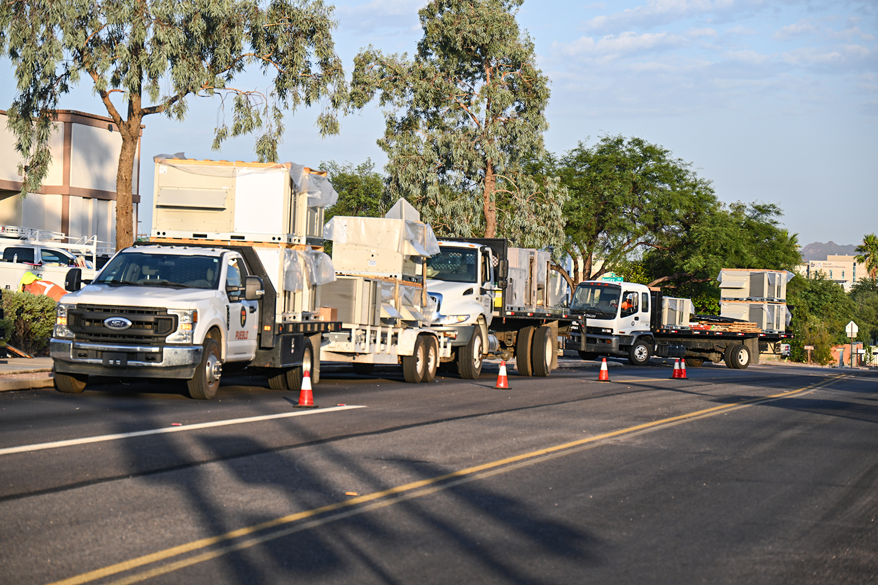 Trucks carrying air conditioners line the street outside Blenman