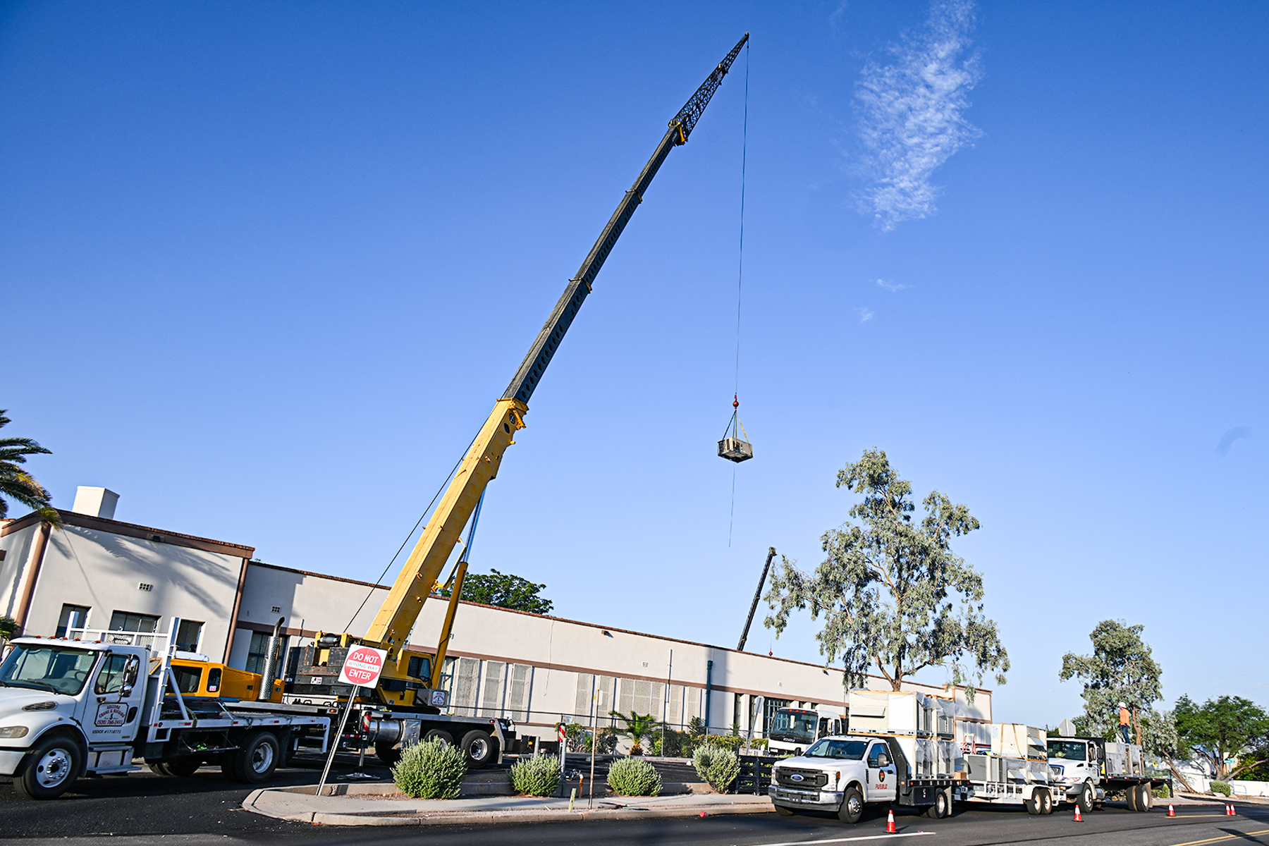 A crane lowers an air conditioner onto Blenman's roof