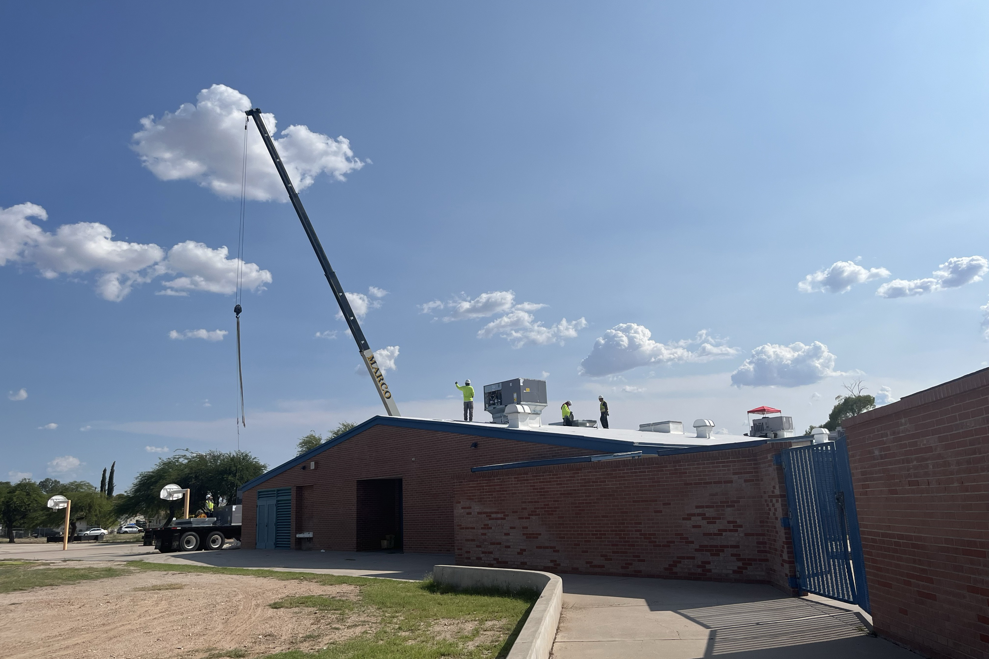 A crane lowers an air conditioner onto the roof of Cavett