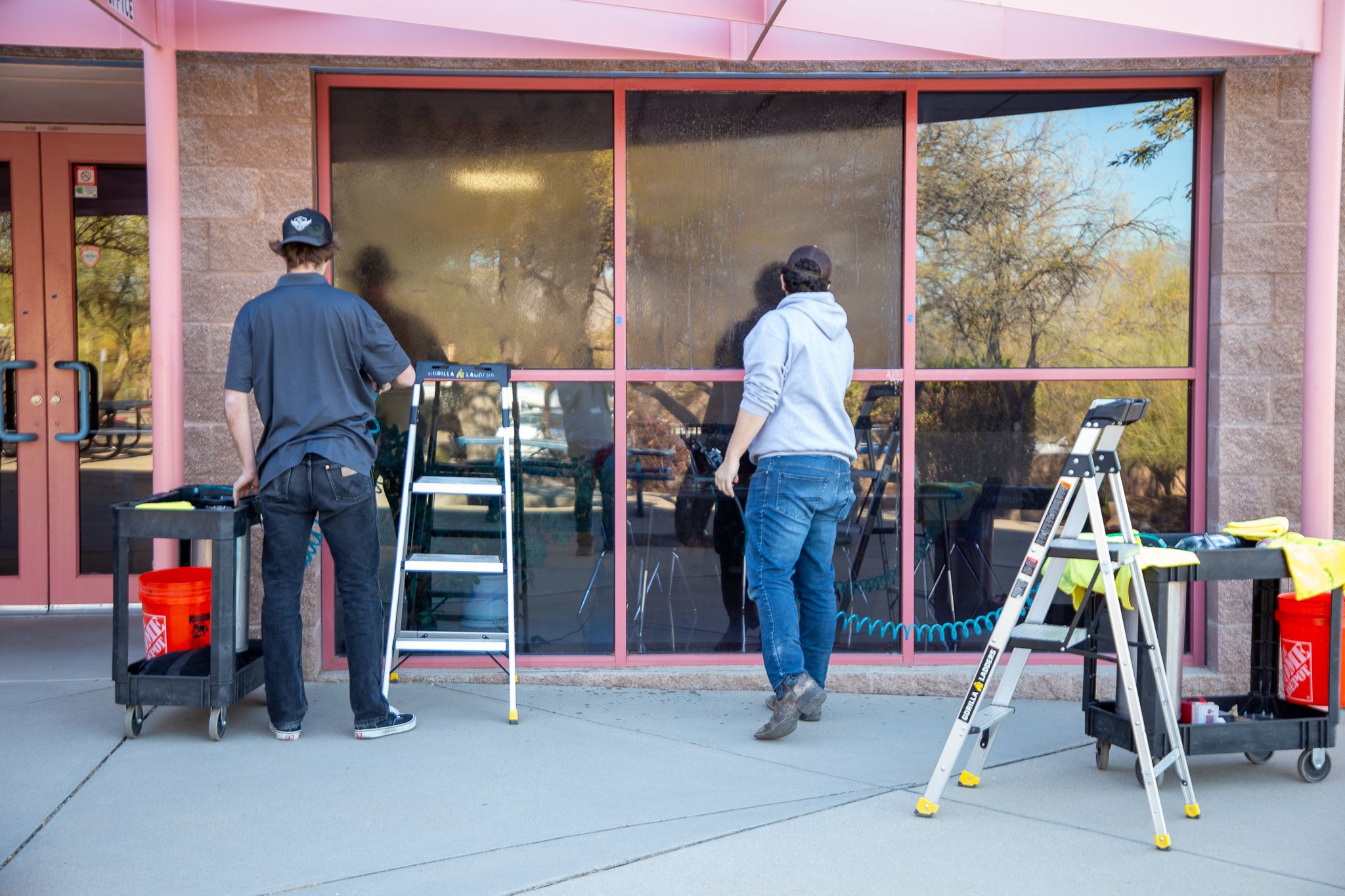 Two men apply security film to the outside windows