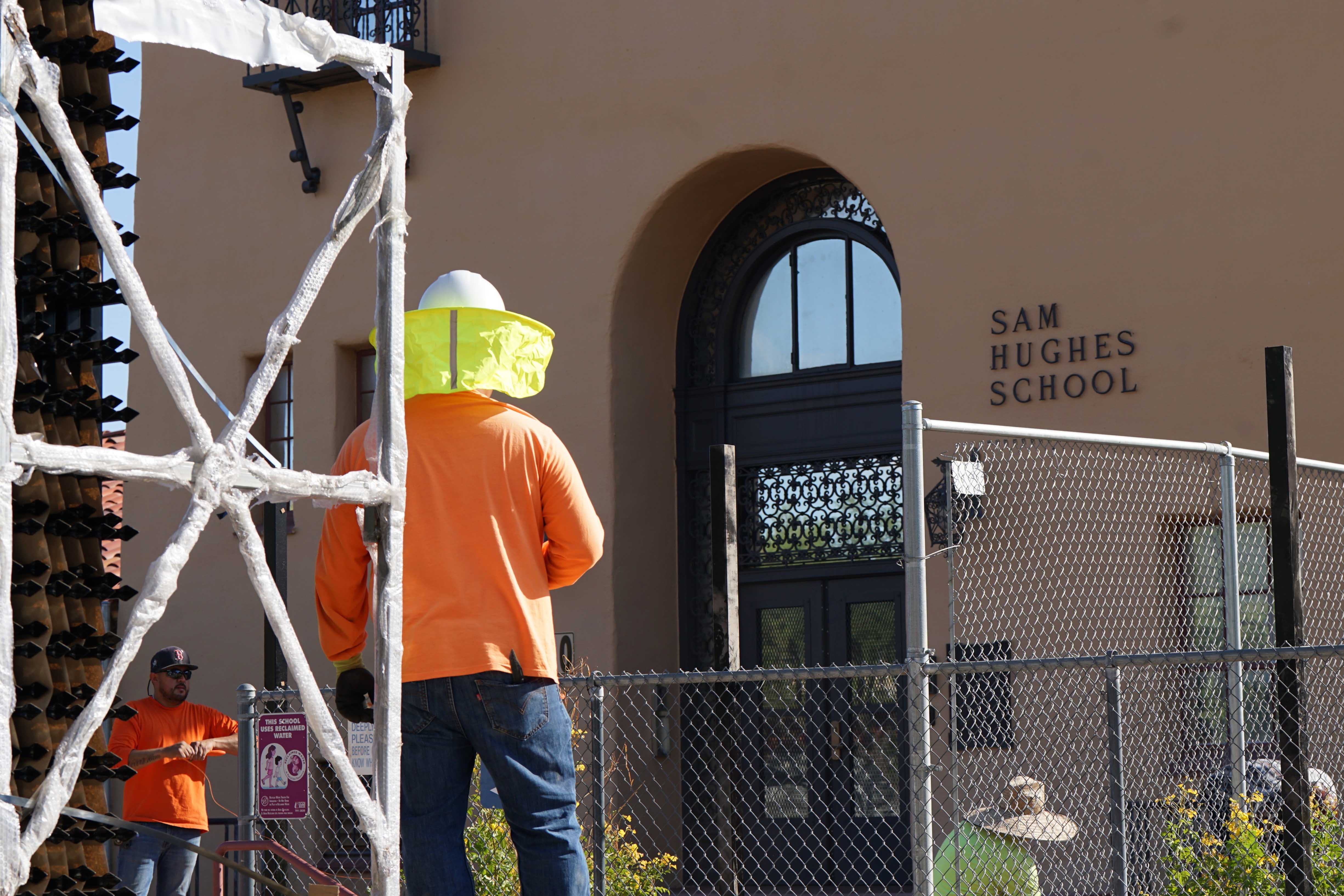 A construction worker in safety gear stands near some scaffolding