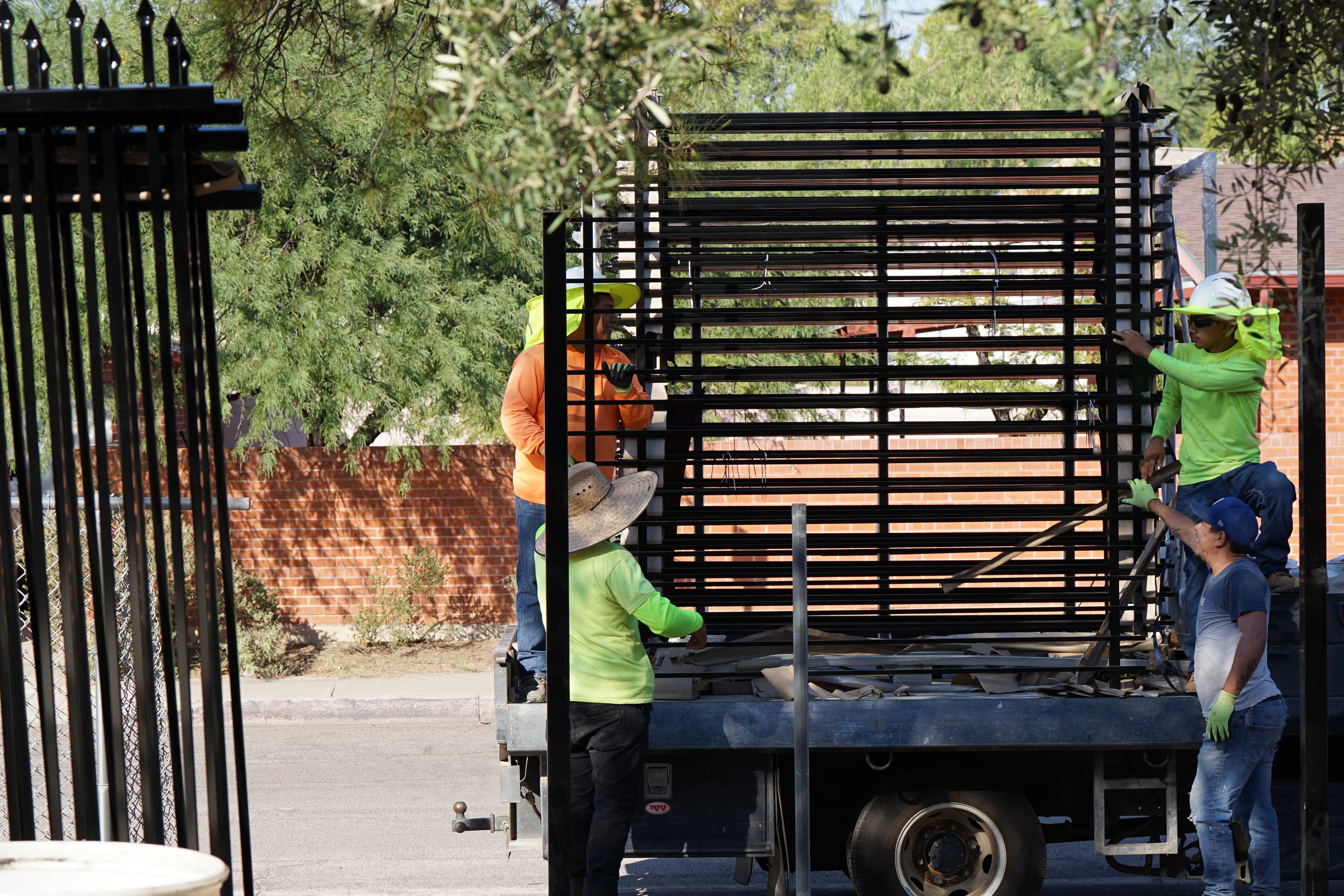 Crews unload new fencing from a truck