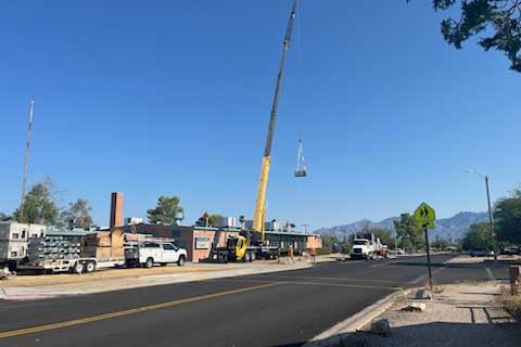 Zoomed out view of a yellow crane lowering an air conditioner