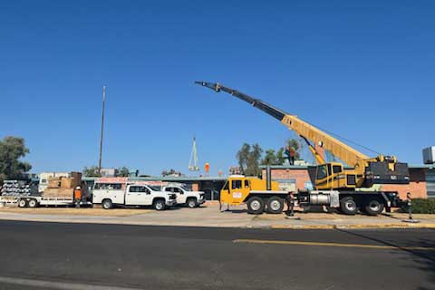 A yellow crane lowers an air conditioner onto Wheeler